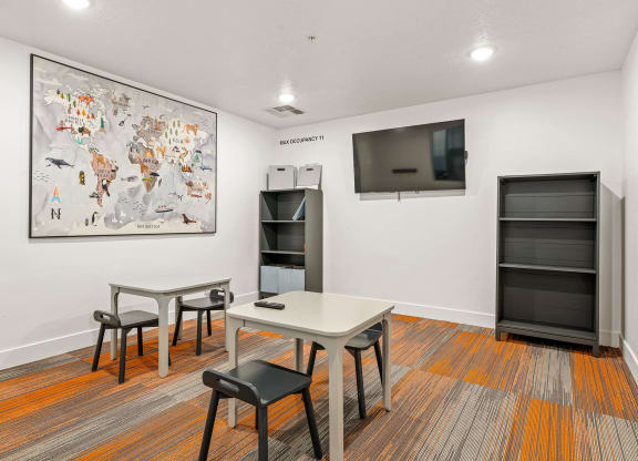 a room with a table and chairs and a television on the wall