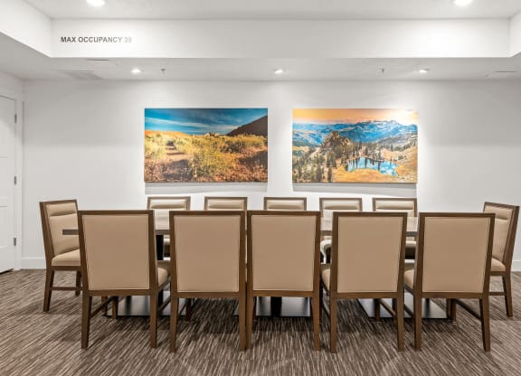 a table with chairs in a room with two paintings on the wall