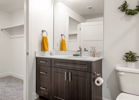 a bathroom with white walls and a dark wood vanity with a white countertop