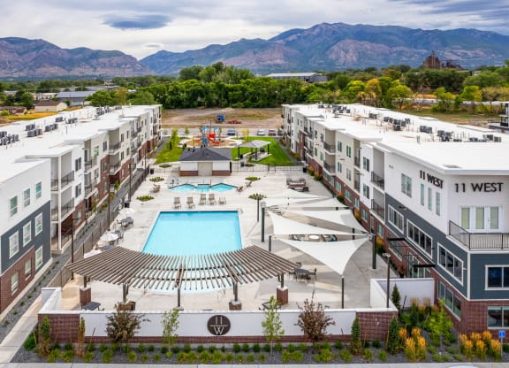 an aerial view of an apartment complex with a pool and mountains in the background