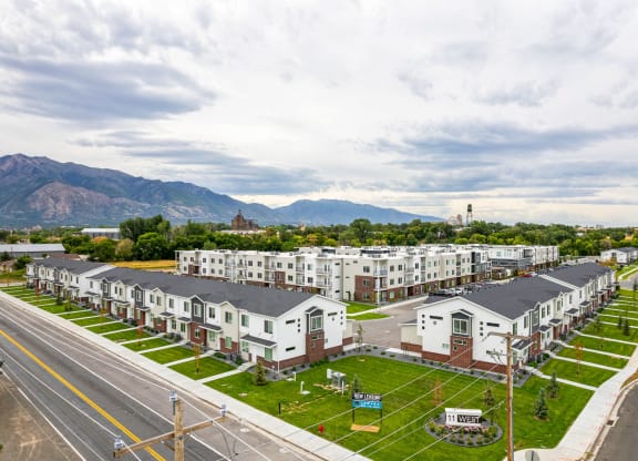 a row of apartment buildings with a street in the foreground and mountains in the background