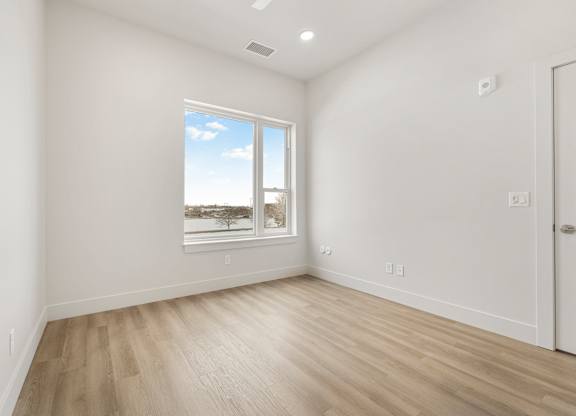 A room with a large window and wooden flooring.