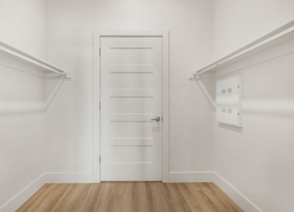 A white door with a handle is in the middle of a room with white walls.