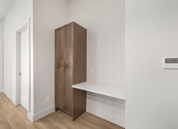 A brown wooden cabinet with a white shelf below it.