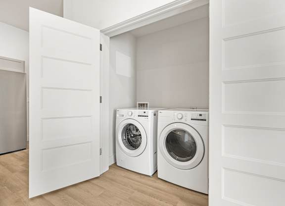 Two white front load washing machines in a laundry room.
