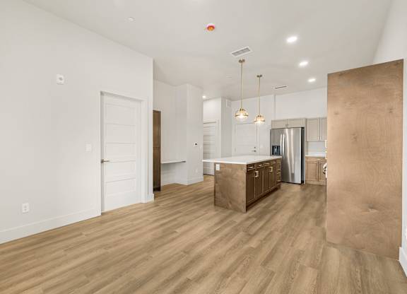 A kitchen area with a white wall and a wooden floor.