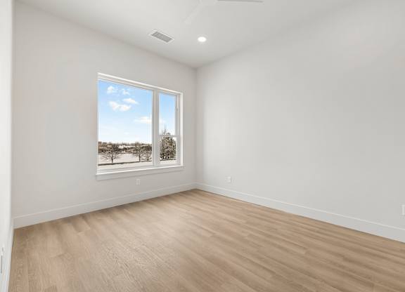 A room with a window showing a view of trees and a blue sky.
