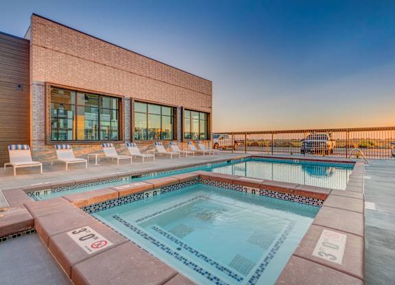 A pool with a red brick building behind it.
