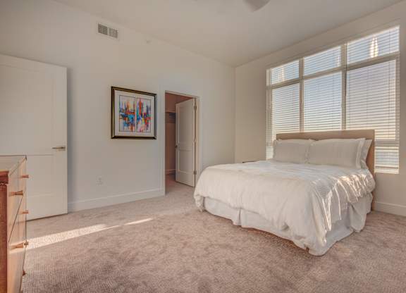 A bedroom with a large bed and a painting on the wall.