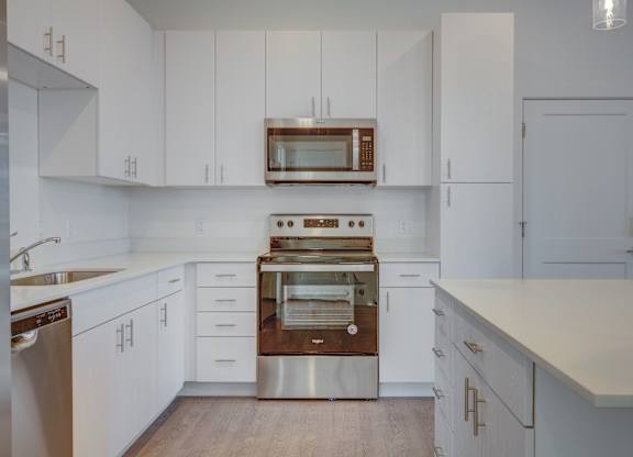 A modern kitchen with white cabinets and stainless steel appliances.