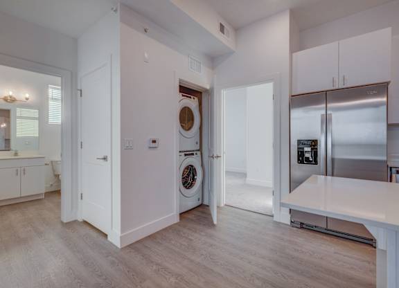 A modern kitchen with white cabinets and a wooden floor.