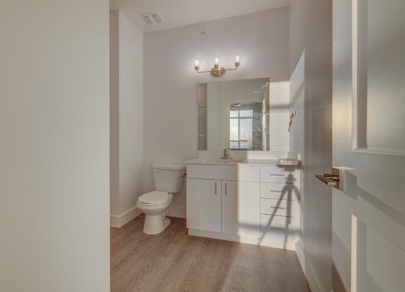 A white bathroom with a toilet, sink, and mirror.