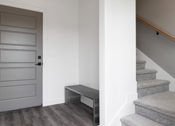 a gray door in a white room with stairs and a radiator