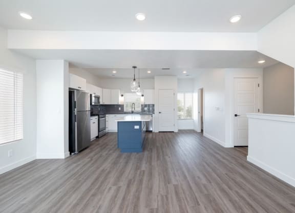 an open kitchen and living room with white walls and wood floors