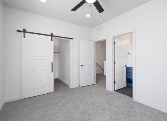 a bedroom with white closets and a ceiling fan