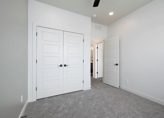 an empty bedroom with two closets and two doors