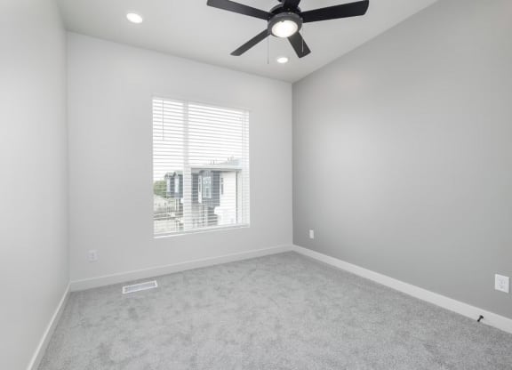 an empty room with a ceiling fan and a window