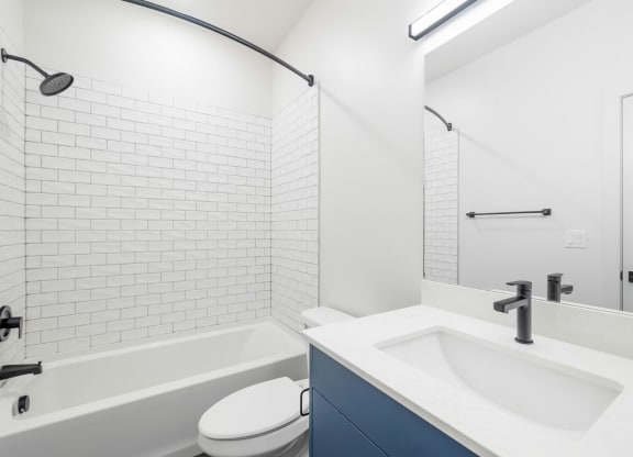 a bathroom with white tiles and a sink and a toilet