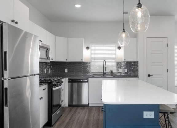 a white kitchen with stainless steel appliances and a blue island