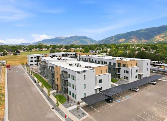 A parking lot in front of a multi-story building with a mountain in the background.