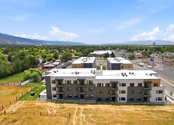 A large white building with a grey roof is surrounded by a grassy field.