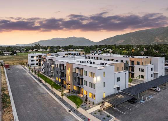A modern apartment complex with a parking lot in front.