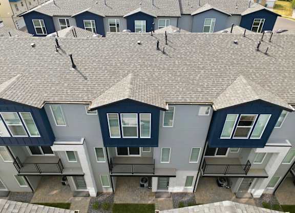 A row of houses with grey roofs and dark blue walls.