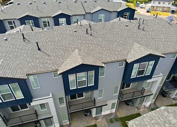 Apartment complex with grey roofs and multiple balconies.