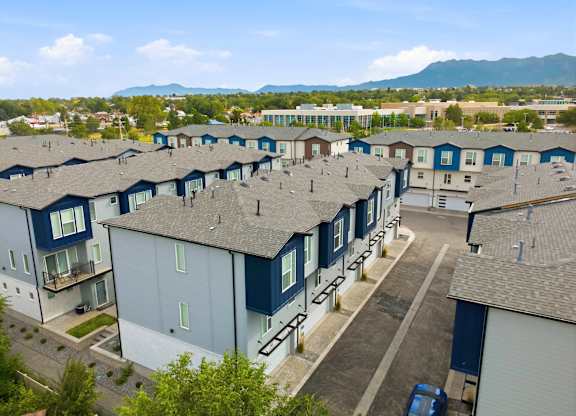 A large apartment complex with multiple buildings and a car parked in the driveway.