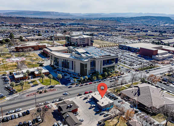 An aerial view of a parking lot with a red pin on a building.