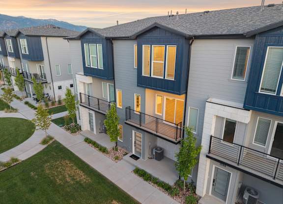 A row of modern townhouses with balconies and a mountain range in the background.