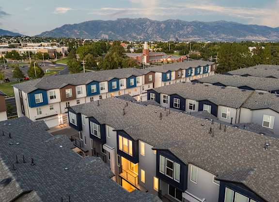 Apartment complex with grey roofs and a mountain range in the background.