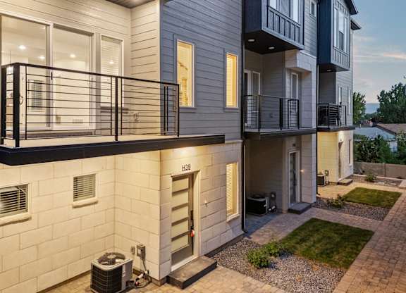 A modern apartment building with a balcony and a small garden area.