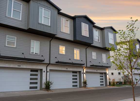A building with grey and white exterior and multiple garage doors.