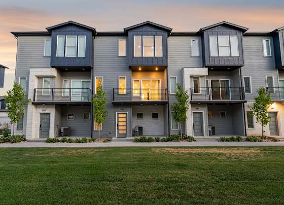 A row of modern townhouses with balconies and garages.