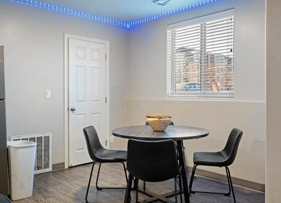 A dining room with a round table and four chairs.