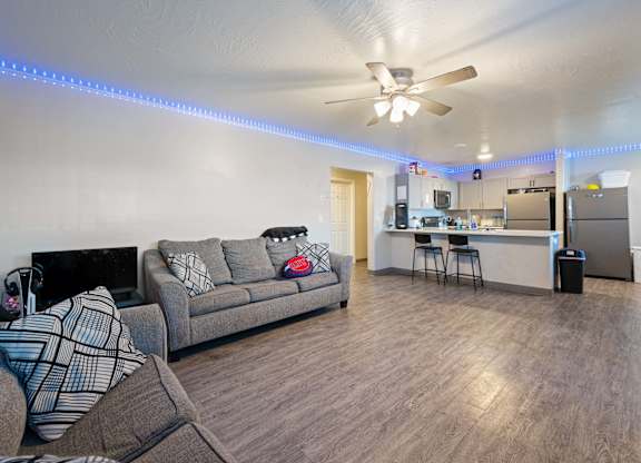 A living room with a grey couch and a ceiling fan.