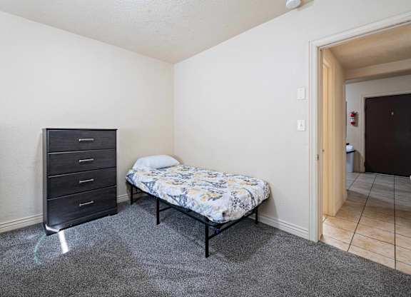 A bedroom with a bed, dresser, and nightstand.