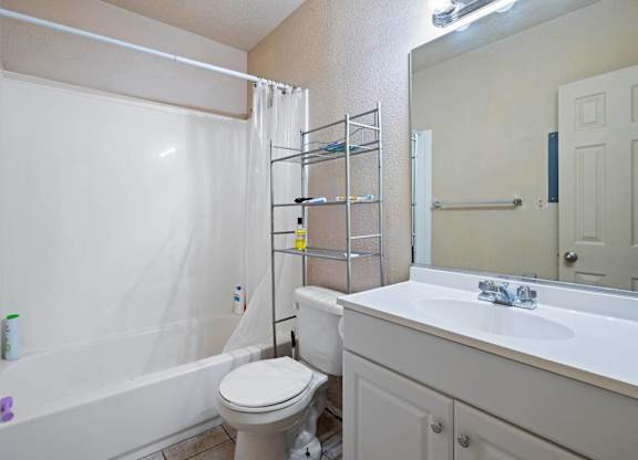 A white bathroom with a toilet, sink, and shower.