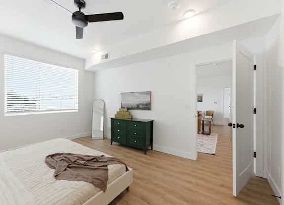 A bedroom with a bed, dresser, and a painting on the wall.