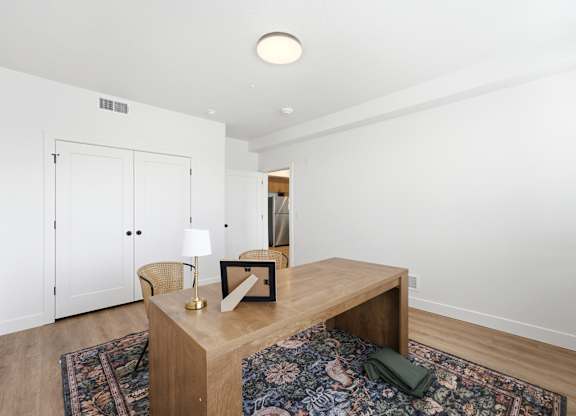 A room with a wooden table and a rug on the floor.