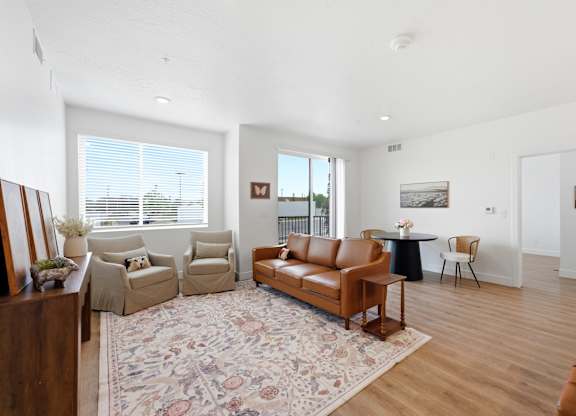 A living room with a brown leather couch and a rug.
