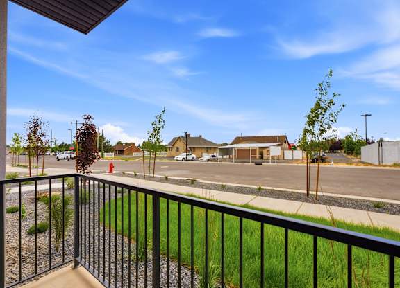 A view from a balcony overlooking a parking lot and a few buildings.