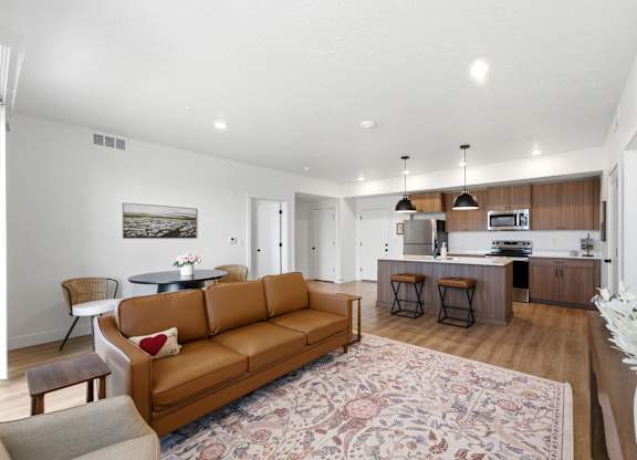 A living room with a brown couch and a rug.