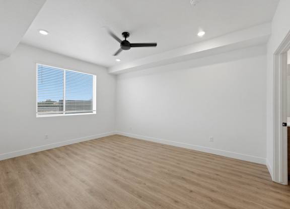 A room with a ceiling fan and a window with blinds.