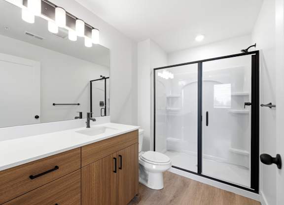 A modern bathroom with a white sink and a walk-in shower.