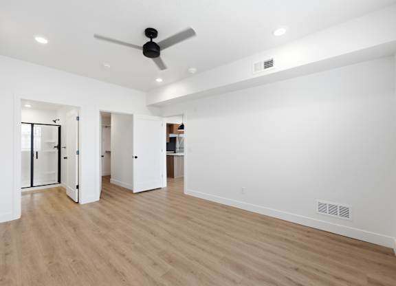 A room with a ceiling fan and wooden flooring.