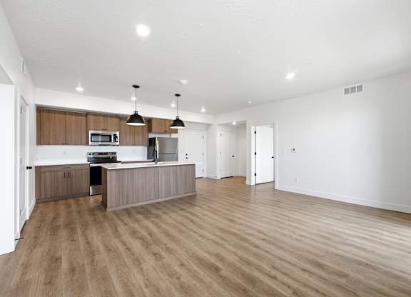 A spacious kitchen with wooden floors and a modern design.