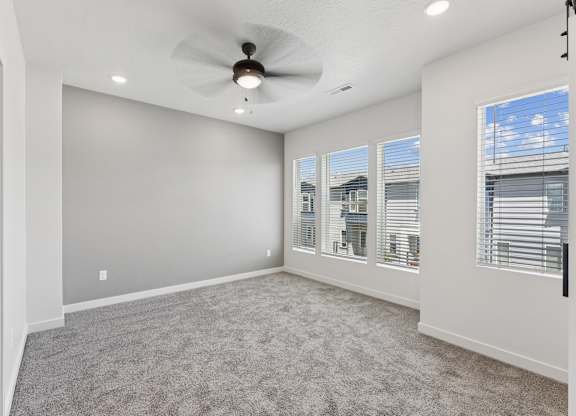 A spacious room with a ceiling fan and large windows.
