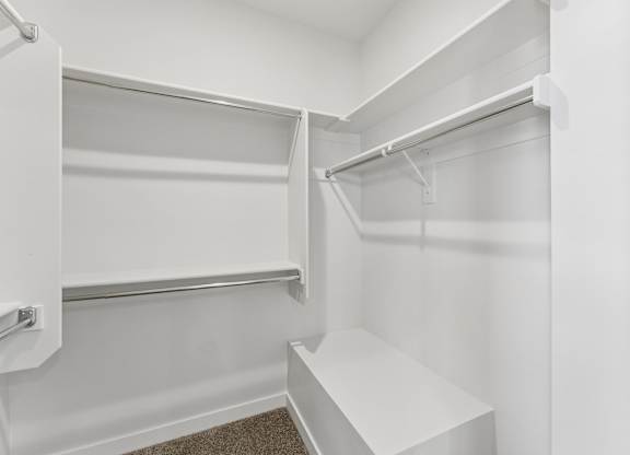 A white closet with a bench and shelves.